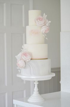 a three tiered white cake with pink flowers on top