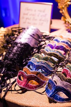 many masks are on display in front of a gold framed mirror and blue lights behind them