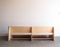 two wooden benches sitting next to each other on the floor in front of a white wall