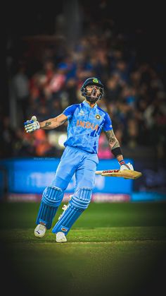 a man in blue uniform holding a bat on top of a field