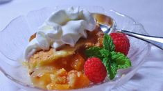 a dessert with whipped cream and raspberries in a glass bowl