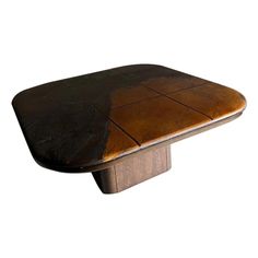 a wooden table topped with a brown leather covered top and square shaped base, on an isolated white background