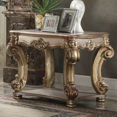 an ornate gold console table with pictures on top and a potted plant next to it