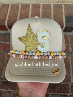 a person holding up a hat with the number five on it and beaded bracelets