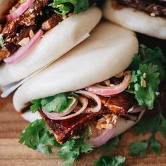 several pita sandwiches with meat, onions and cilantro on a cutting board