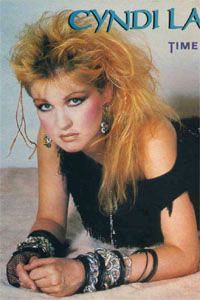 a woman laying on top of a bed wearing bracelets and black dress with her hands behind her head