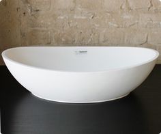 a large white bowl sitting on top of a black table next to a brick wall