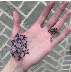 a person's hand with a flower tattoo on the middle of their left palm