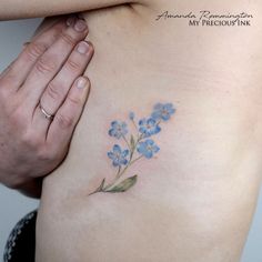 a woman's stomach with small blue flowers on her left side ribcage