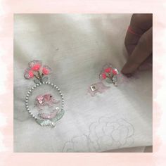 two brooches with pink flowers on them are being stitched onto the fabric