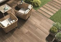 two wicker chairs sitting on top of a wooden floor next to a green lawn