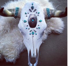 a cow skull with turquoise and white beads on it