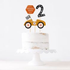 a white cake topped with a number two and a race car on top of it