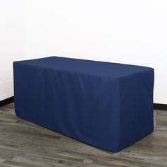 a blue table cover sitting on top of a hard wood floor next to a white wall