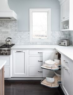 a kitchen with white cabinets and marble backsplash