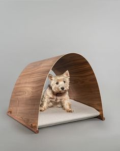 a small dog is sitting in a wooden pet bed that's shaped like an arch