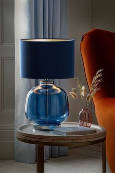 a blue lamp sitting on top of a table next to a red chair and orange chair