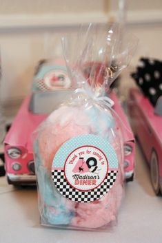 a pink toy car next to a plastic bag filled with cotton balls and other toys