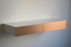 a white shelf with two wooden drawers on it's sides, against a wall