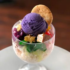 an ice cream sundae with cookies and other toppings in a glass bowl on a white plate