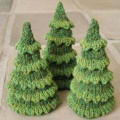 three knitted christmas trees sitting on the ground