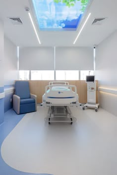 an empty hospital room with a skylight above the bed and chairs around the table