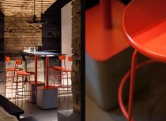 an orange table and stools in a room with exposed brick walls on either side