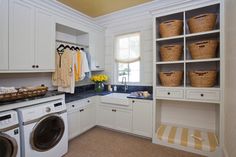 a washer and dryer in a white laundry room with baskets on the shelves