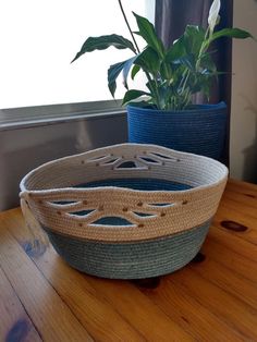 two baskets sitting on top of a wooden table next to a plant in a pot