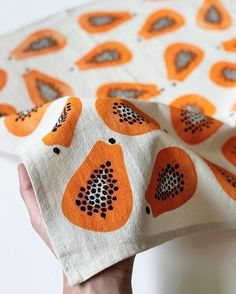 a hand holding an orange and white fabric with black dots on it's edges