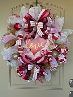 a valentine's day wreath with the word love written in gold, red and white