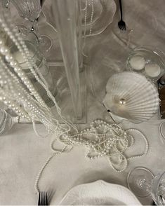 the table is set with white dishes and silverware, including pearl beaded place settings