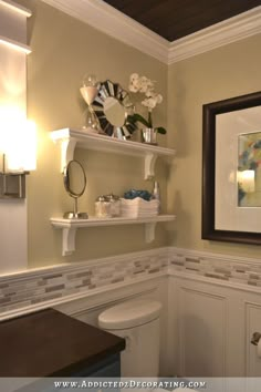 a white toilet sitting next to a bathroom sink under a framed art print on the wall