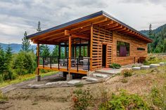 a small wooden cabin sitting on top of a hill next to a lush green forest