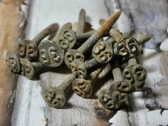 an assortment of old rusty nails with faces on them sitting on top of a wooden table