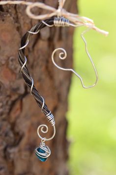 a wire wrapped necklace hanging from a tree