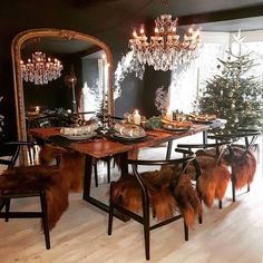 a dining room table with chairs and a mirror on the wall next to christmas trees