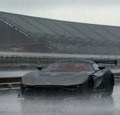 a sports car driving on a wet track in front of an empty bleachers