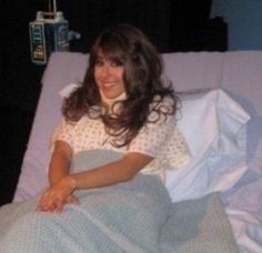 a woman in a hospital bed smiling for the camera