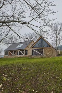 a house sitting on top of a lush green field next to a forest filled with trees