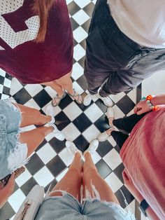 four people are standing in a circle on a checkered floor with their legs crossed