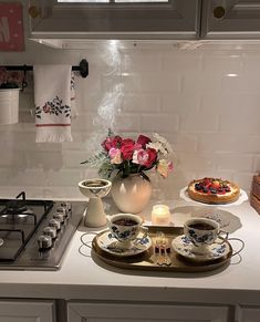 a white kitchen counter topped with plates and cups filled with food next to a stove top