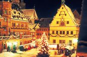 a christmas tree is lit up in the middle of an old european town at night