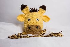 a crocheted giraffe head with brown ears and black eyes on a white background