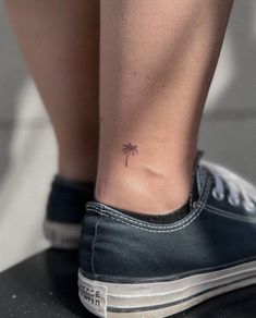 a small palm tree tattoo on the right side of her ankle, which is attached to a black tennis shoe