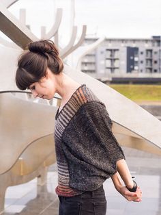 a woman standing in front of a sculpture with her back to the camera and looking down