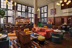 a living room filled with lots of furniture and tall windows next to a bar area