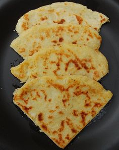 three flat breads are on a black plate