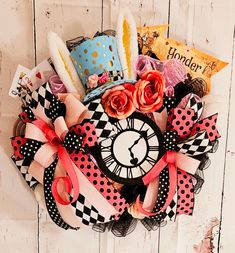 a clock decorated with ribbons and flowers on a white wooden wall next to some books