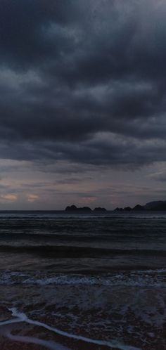 two people walking on the beach at dusk